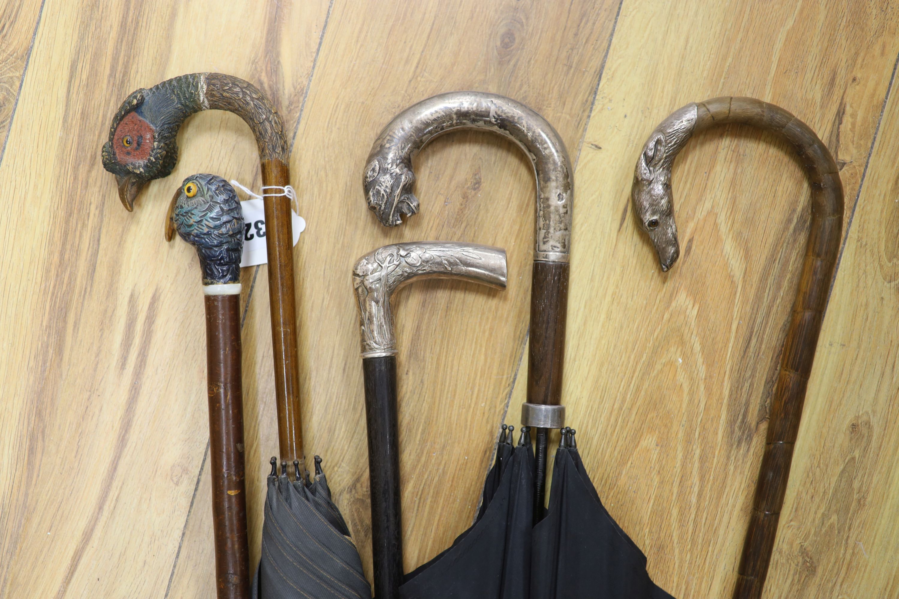 A white metal mounted cane, possibly Hanau?, another white metal dog head mounted walking cane, a white metal jaguar head parasol,